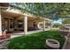 Extended covered patio with manicured lawn, desert landscaping, and mature trees at 16769 W Brookhaven Ct, Surprise, AZ 85387