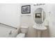 Small white powder room with pedestal sink, round mirror, and grab bar at 16769 W Brookhaven Ct, Surprise, AZ 85387