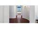 Hallway with hardwood floors and white walls leading to the bathroom with blue window treatments at 16769 W Brookhaven Ct, Surprise, AZ 85387