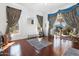 Living room with hardwood floors, large windows with curtains, and sliding glass doors to the patio at 16769 W Brookhaven Ct, Surprise, AZ 85387