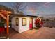 Charming exterior featuring a red door, white siding, and a pergola on a concrete patio, perfect for outdoor enjoyment at 17335 W Cheryl Dr, Waddell, AZ 85355