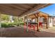 Inviting covered patio and outdoor kitchen area featuring a stylish pergola and bar with red stools at 17335 W Cheryl Dr, Waddell, AZ 85355