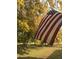 American flag waves proudly in the yard, surrounded by mature trees with fall foliage and green grass at 17335 W Cheryl Dr, Waddell, AZ 85355