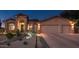 Charming single-story home with a two-car garage and desert landscaping illuminated at twilight at 17366 E Via Del Oro St, Fountain Hills, AZ 85268