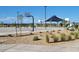 Community basketball court featuring multiple basketball hoops, shaded seating, and desert landscaping at 18334 W Desert Holw Dr, Wittmann, AZ 85361