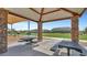 Community picnic area with shaded picnic tables, stone column supports and view of the lawn at 18334 W Desert Holw Dr, Wittmann, AZ 85361