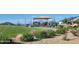 Community playground featuring play structures on green lawn with bench seating and shade at 18334 W Desert Hollow Dr, Wittmann, AZ 85361