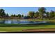 Picturesque golf course with a tranquil pond, fountain, vibrant green grass, and lush mature trees at 25821 S Hollygreen Dr, Sun Lakes, AZ 85248