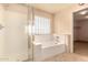 A bright bathroom featuring a glass door shower, soaking tub, and tile flooring at 25845 W Lynne Ln, Buckeye, AZ 85326