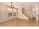 A bright living room with tile floors, a chandelier, windows, and a staircase at 25845 W Lynne Ln, Buckeye, AZ 85326