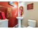 Charming half bathroom features red accent wall and stylish pedestal sink at 2868 E Dunbar Dr, Phoenix, AZ 85042