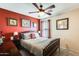 Charming bedroom with red accent wall, wood furniture, ceiling fan and decorative wall art at 2868 E Dunbar Dr, Phoenix, AZ 85042