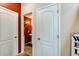 Hallway view showing a glimpse into a half bathroom with a vibrant red accent wall at 2868 E Dunbar Dr, Phoenix, AZ 85042