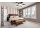 Cozy bedroom with a ceiling fan, striped accent wall, plantation shutters and neutral color palette at 29986 N Jillian Dr, San Tan Valley, AZ 85143