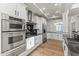 Bright kitchen with white cabinetry, stainless steel appliances, black countertops and hardwood floors at 302 W Stella Ln, Phoenix, AZ 85013