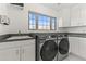 Well-lit laundry room with modern appliances, sleek cabinets, sink, and a window offering natural light at 302 W Stella Ln, Phoenix, AZ 85013