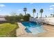 Private backyard pool surrounded by a lush green lawn and well manicured shrubs and palm trees at 302 W Stella Ln, Phoenix, AZ 85013