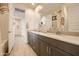 Bathroom with a dual sink vanity, quartz countertop, decorative jars, and a view to the hallway at 38233 N Stillmeadow Rd, San Tan Valley, AZ 85140