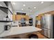 Well-lit kitchen featuring stainless steel appliances, white countertops and subway tile, wood cabinets and two barstools at 40265 N Acadia Ct, Anthem, AZ 85086