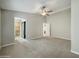 Spacious main bedroom with plush carpeting, ceiling fan, and an open doorway to an ensuite bathroom at 8661 N 108Th Ln, Peoria, AZ 85345