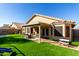 Lush backyard with a covered patio, artificial grass, and outdoor seating at 9853 W Irma Ln, Peoria, AZ 85382