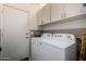 Bright laundry room with a white front-load washer and dryer and ample storage space at 9853 W Irma Ln, Peoria, AZ 85382