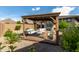 Covered backyard patio features stylish outdoor seating and a tranquil desert-landscaped yard at 13224 W Crimson Ter, Peoria, AZ 85383