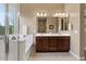 Bathroom featuring double sinks with dark cabinetry, a walk-in glass shower, and a large soaking tub at 13583 S 177Th Ln, Goodyear, AZ 85338