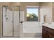 Bright bathroom featuring a walk-in shower and large soaking tub, with neutral-toned tile and dark wood cabinets at 13583 S 177Th Ln, Goodyear, AZ 85338