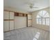 Bedroom with a large arched window, built in shelves and cabinets, neutral carpet and a ceiling fan at 13914 W Terra Vista Dr, Sun City West, AZ 85375