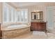 Elegant bathroom features marble-encased tub under decorative windows, and vanity with granite counter and wood cabinetry at 1440 N 40Th St # 4, Mesa, AZ 85205