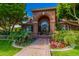 Elegant brick home with arched entrance, decorative door, and colorful flower beds lining the walkway at 1440 N 40Th St # 4, Mesa, AZ 85205