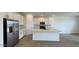 Modern kitchen featuring stainless steel appliances, white cabinets, an island, and open access to the living area at 15761 W Beryl Ave, Waddell, AZ 85355