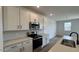 Close-up of the modern kitchen, featuring white cabinets, quartz countertops, a tile backsplash, and stainless steel appliances at 15761 W Beryl Ave, Waddell, AZ 85355