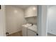 A functional laundry room with a white washer and dryer and shelving for storage at 15761 W Beryl Ave, Waddell, AZ 85355