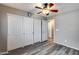 Bedroom with wood-look floors, three closets, and ceiling fan at 162 N 225Th Dr, Buckeye, AZ 85326