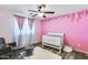 Charming Bedroom with pink walls, a white crib, and a ceiling fan at 162 N 225Th Dr, Buckeye, AZ 85326