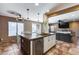 Kitchen island with stone countertop, wooden accents, and pendant lighting, connecting to the living area at 162 N 225Th Dr, Buckeye, AZ 85326