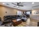 Cozy living room with wood floors, a leather sofa, wooden table, and a ceiling fan for comfortable relaxation at 162 N 225Th Dr, Buckeye, AZ 85326