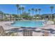 Beautiful community pool featuring a clear blue pool, shady areas, lounge chairs, and palm trees at 17190 W Bent Tree Dr, Surprise, AZ 85387