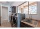 Modern laundry room with side-by-side washer and dryer, convenient sink, and sun-filled window at 22970 N 79Th Pl, Scottsdale, AZ 85255