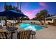 Beautiful backyard pool features a sitting area, a blue sun umbrella, and lush landscaping at sunset at 25 W Frier Dr, Phoenix, AZ 85021