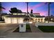 A modern home with a three-car garage, desert landscaping, and illuminated windows at dusk at 25 W Frier Dr, Phoenix, AZ 85021