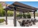 Outdoor kitchen featuring a built-in grill, bar seating, and a stylish pergola at 25436 N 114Th St, Scottsdale, AZ 85255