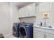 Efficient laundry room boasts modern blue washer and dryer under white cabinets at 3483 W Verde River Rd, San Tan Valley, AZ 85144