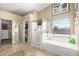 Spacious bathroom featuring a tub, shower, and closet, with light colored tile floors at 3608 N Mansfield Dr, Litchfield Park, AZ 85340