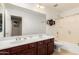 Bright bathroom features a dual sink vanity, large mirror, and shower-tub combo with neutral tile flooring at 3608 N Mansfield Dr, Litchfield Park, AZ 85340