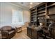 Inviting home office with custom built-ins, a cozy leather chair, and ample natural light for a productive workspace at 36276 N Secret Garden Path, Queen Creek, AZ 85140