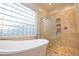 Bright bathroom features a freestanding tub, glass block window, and stylish, tiled shower with glass enclosure at 4251 E Desert Forest Trl, Cave Creek, AZ 85331