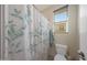 Small bathroom with patterned shower curtain, tiled floors, and a small window at 5121 N 181St Dr, Litchfield Park, AZ 85340